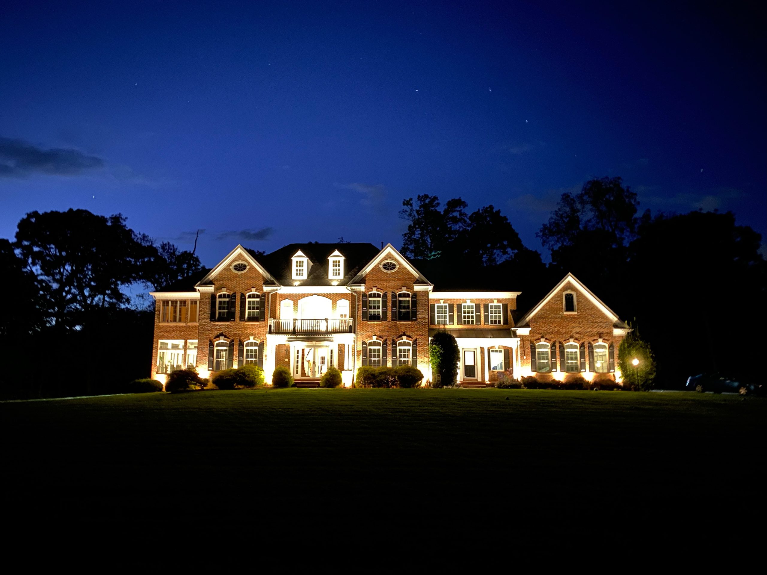 Large house lit up brightly at night with dark blue sky